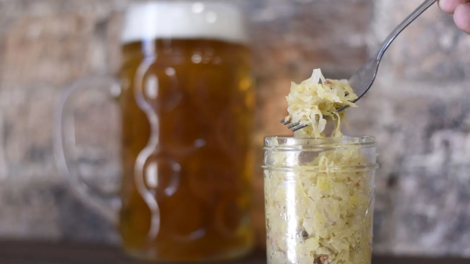 Gläser mit fermentiertem Gemüse und Weißkohl auf einem Holztisch