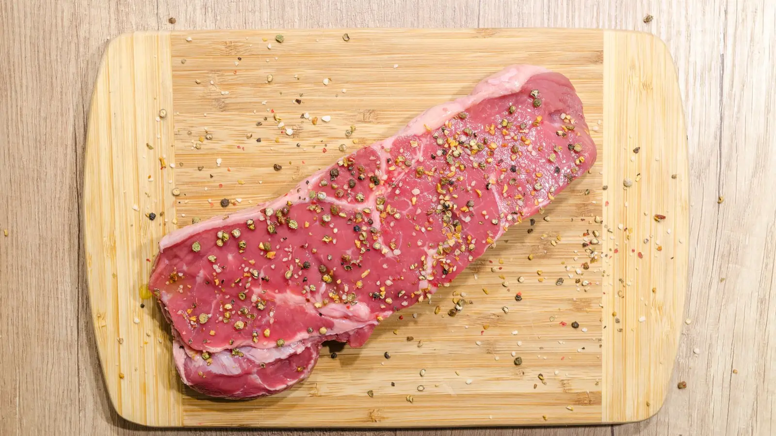 Rohe Rindersteaks auf einem Holzbrett mit Rosmarin